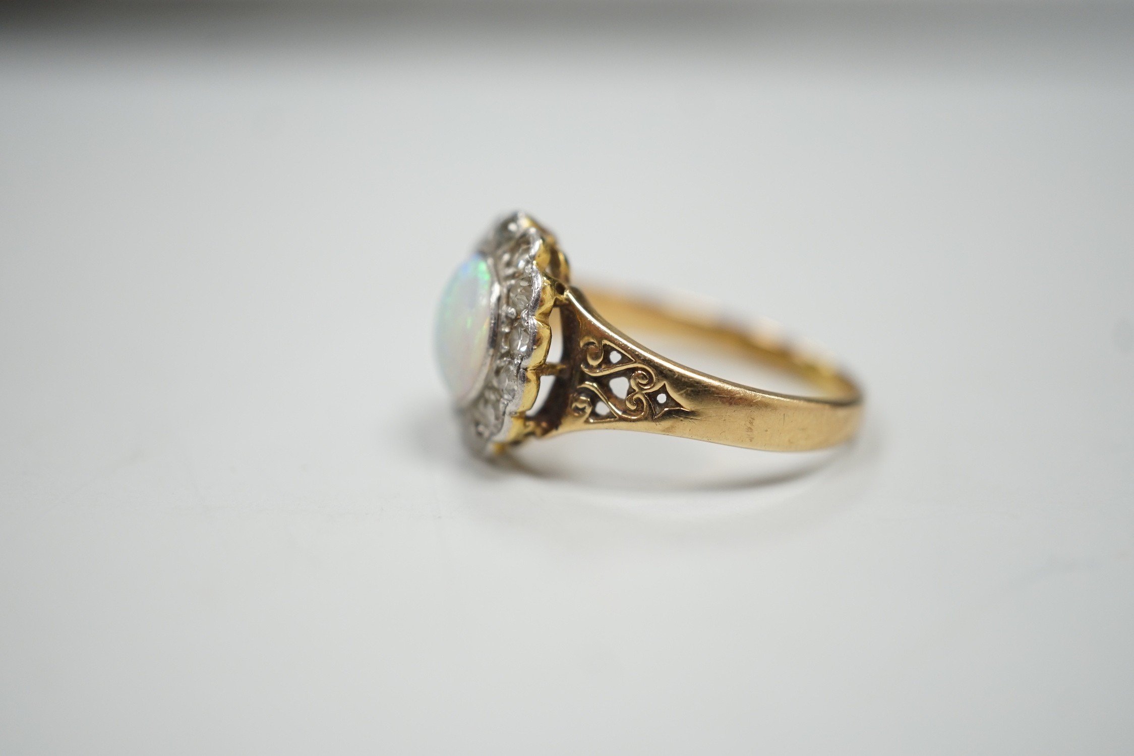 A 1920's? yellow metal, white opal and round cut diamond set circular cluster ring, size O, gross weight 3.6 grams.